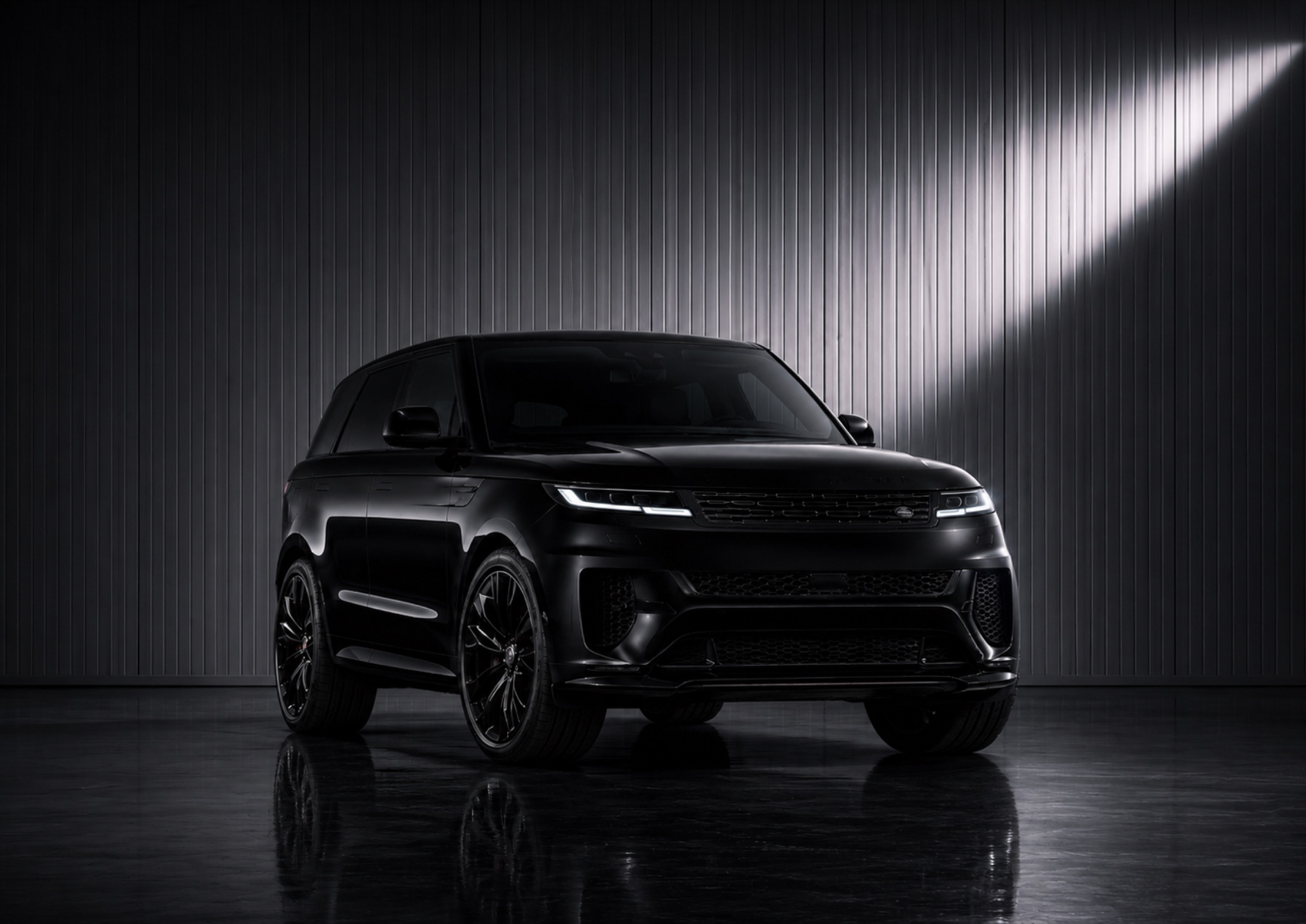 A black Range Rover Sport in a dark studio under a shaft of light